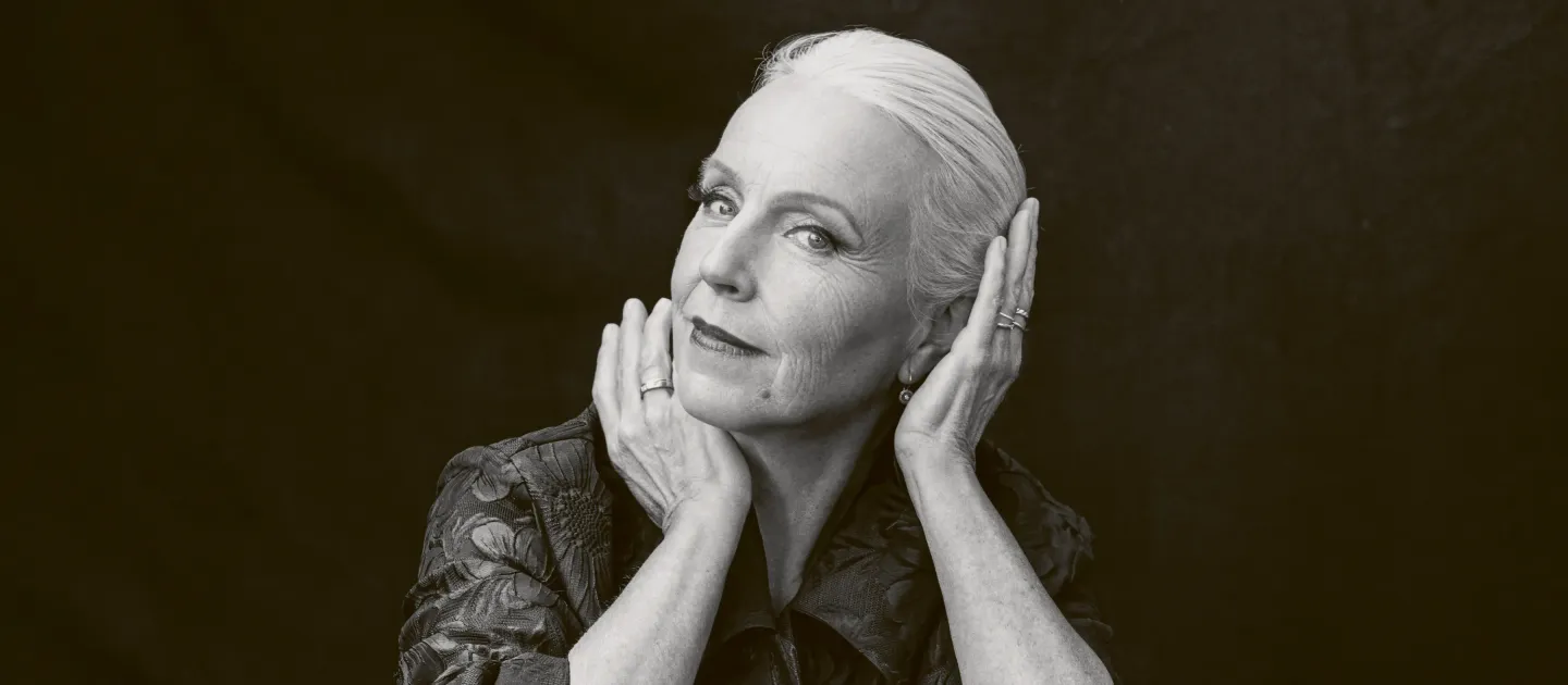 schwarz-weiß Portrait von älterer Dame mit weißen Haaren. Sie stützt Kopf auf Hände