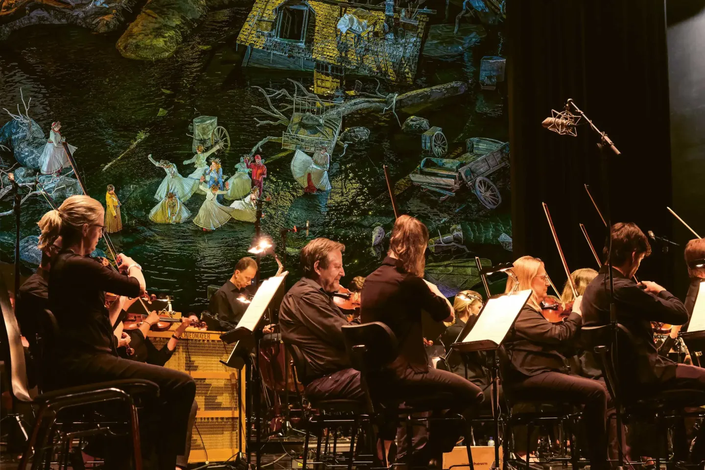 © Bregenzer Festspiele / Eva Cerv Die Wiener Symphoniker im Großen Saal im Hintergrund ist eine Szene aus der Freischütz zu sehen, die als Video übertragen wird.