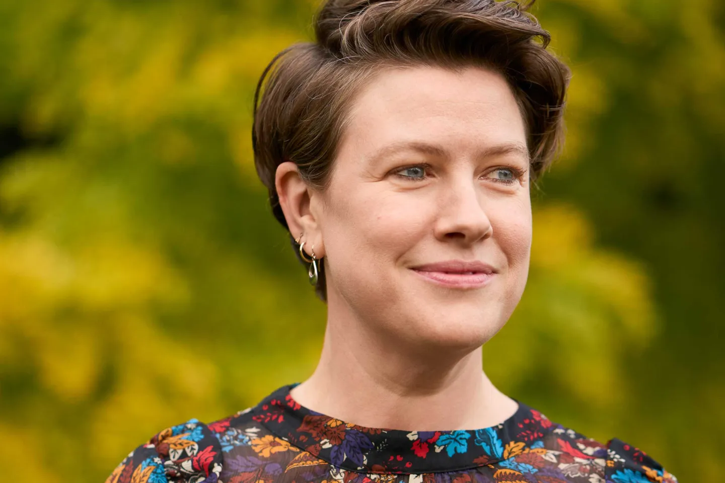 Regisseurin Amy Lane: Portrait, kurze Haare, lächelnd vor grünem Hintergrund