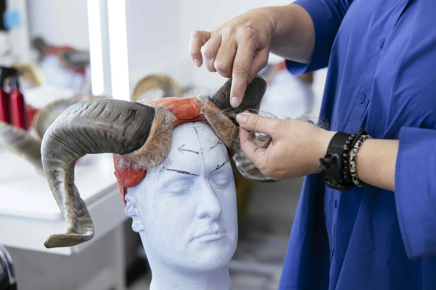 © Bregenzer Festspiele / Lisa Mathis Die Hörner von Teufel Samiel aus "Der Freischütz" auf einer Puppe, zwei Hände arbeiten an den Haaren