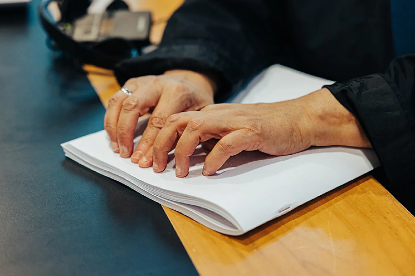 © Colin Michel Hände ertasten ein aufgeschlagenes Braillebuch auf einem Tisch