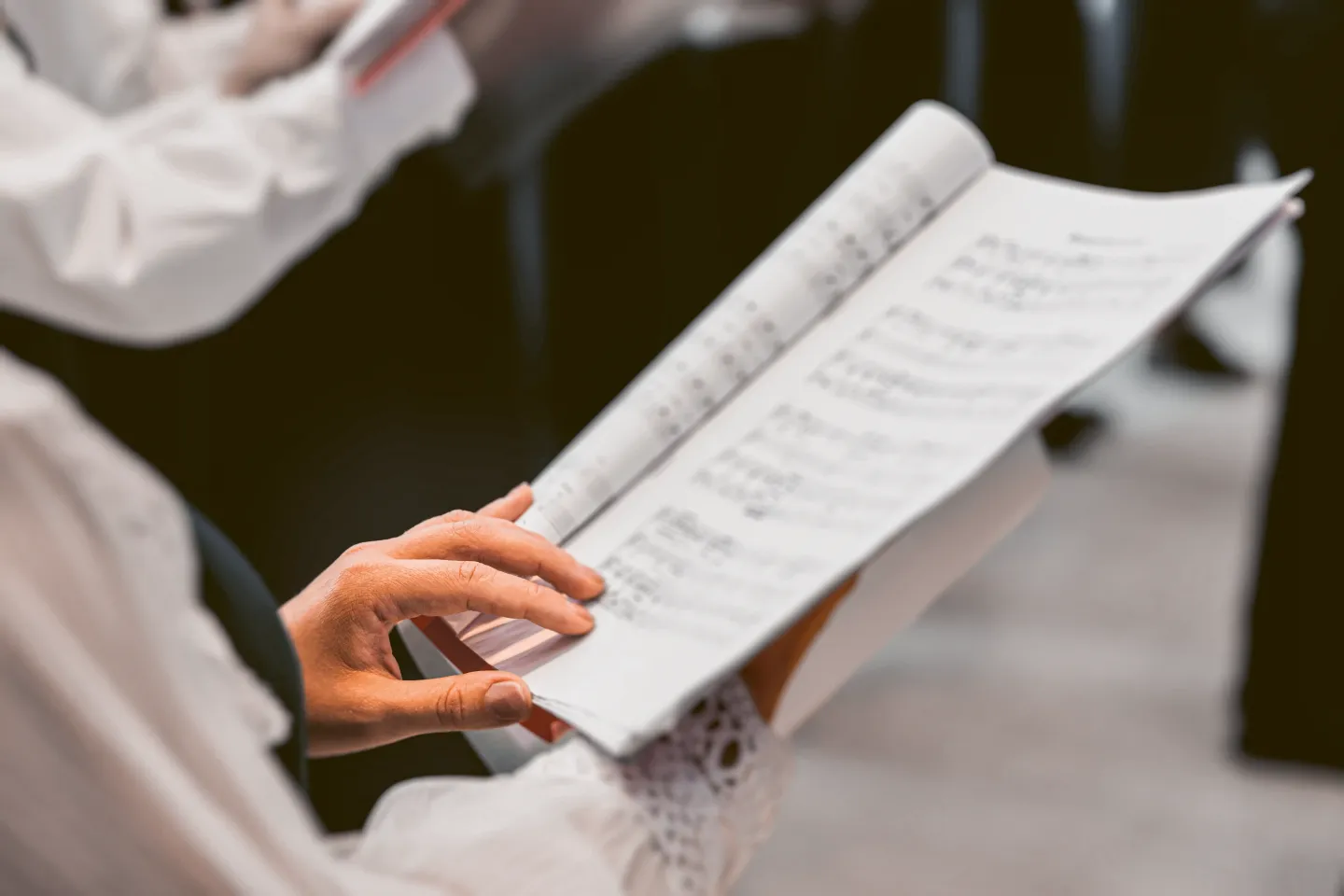 Hand hält ein aufgeklapptes Notenheft mit sichtbaren Notenzeilen