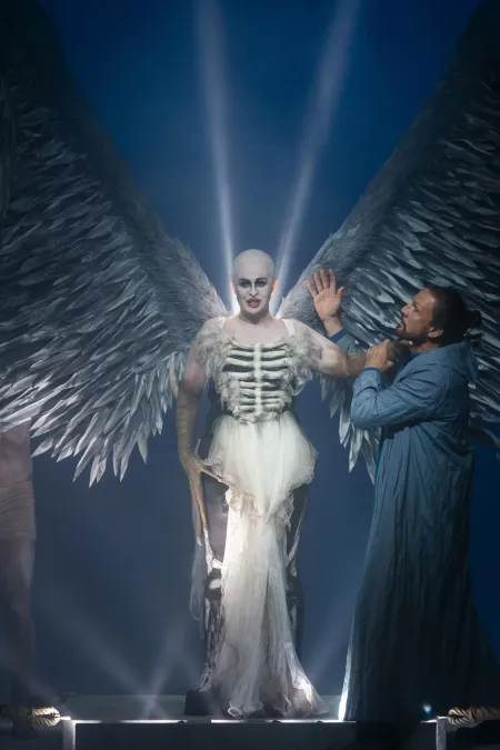 Szene aus "Œdipe", 2025 im Festspielhaus, Anna Danik (La Sphinge) im Sphinx-Kostüm und in Schweinwerferlicht, rechts Paul Gay (Œdipe), dunkler Hintergrund