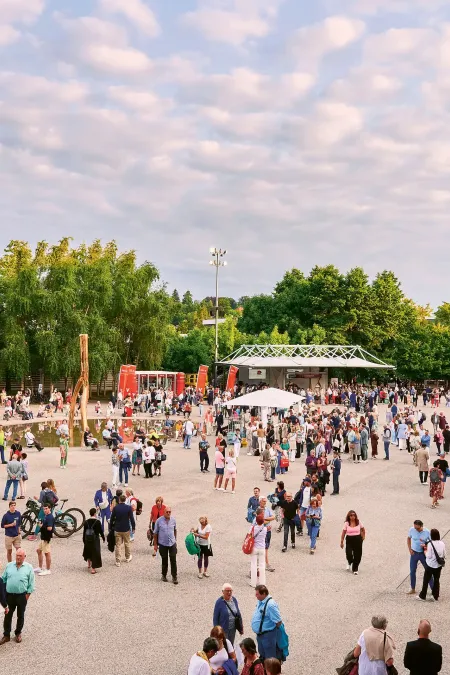 Große Menschenmenge auf Festspielplatz mit Bäumen im Hintergrund. und teilweise bewölktem Himmel