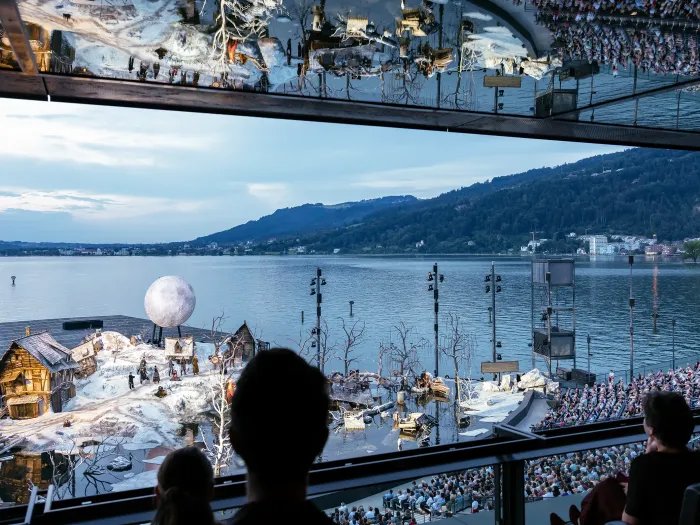Blick aus der Festspiellounge auf das Bühnenbild "Der Freischütz" - eine verschneite Landschaft - und den Bodensee