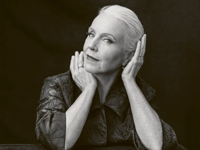schwarz-weiß Portrait von älterer Dame mit weißen Haaren. Sie stützt Kopf auf Hände