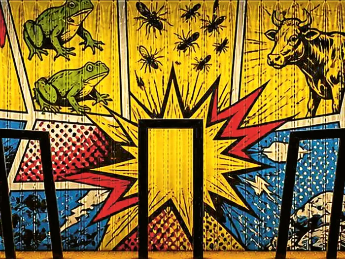 Popart-Wand mit Frosch, Insekten, Kuh und abstrakten Explosionselementen hinter drei schwarzen Barhockern