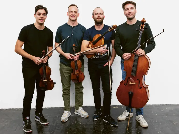 © Niesel-Reghenzani Vier Männer stehen nebeneinander und halten Streichinstrumente, zwei Geigen, eine Bratsche und ein Cello.