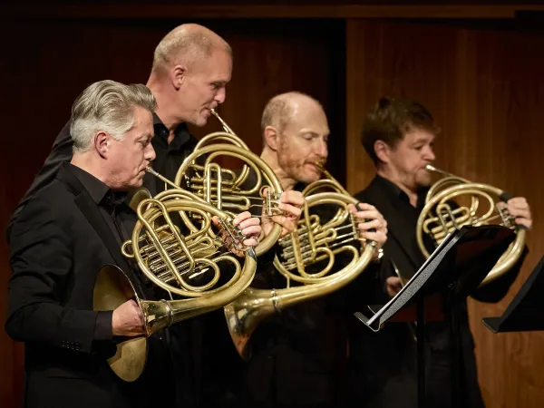 © Bregenzer Festspiele / Anja Koehler Fünf Musiker in schwarzer Kleidung spielen Hörner. Der erste Musiker hält ein großes, gebogenes Horn, während die anderen drei ihre Instrumente in der Hand halten.
