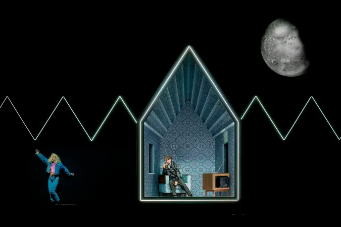 Silhouette einer tanzenden Person links, mittig eine Person in einem stilisierten, beleuchteten Haus mit gemusterten Wänden und einem alten Fernseher, rechts ein großer Mond vor schwarzem Hintergrund