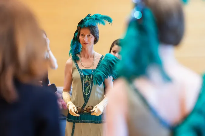 © Bregenzer Festspiele / Kristina Becker Frau in grünem Kostüm mit Federhaarschmuck und langen Handschuhen steht in einem Raum und hält ein Accessoire
