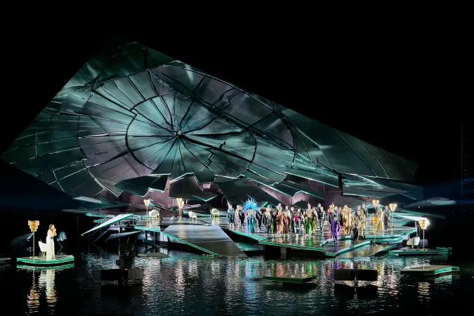 © Bregenzer Festspiele / Anja Koehler Bühnenbild mit großer, zerbrochener Uhr als Kulisse und Ensemble auf einer Wasserbühne bei einer Opernaufführung